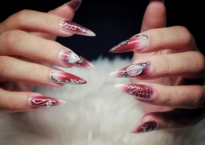 Woman's hands with long, ornate red and white stiletto nails